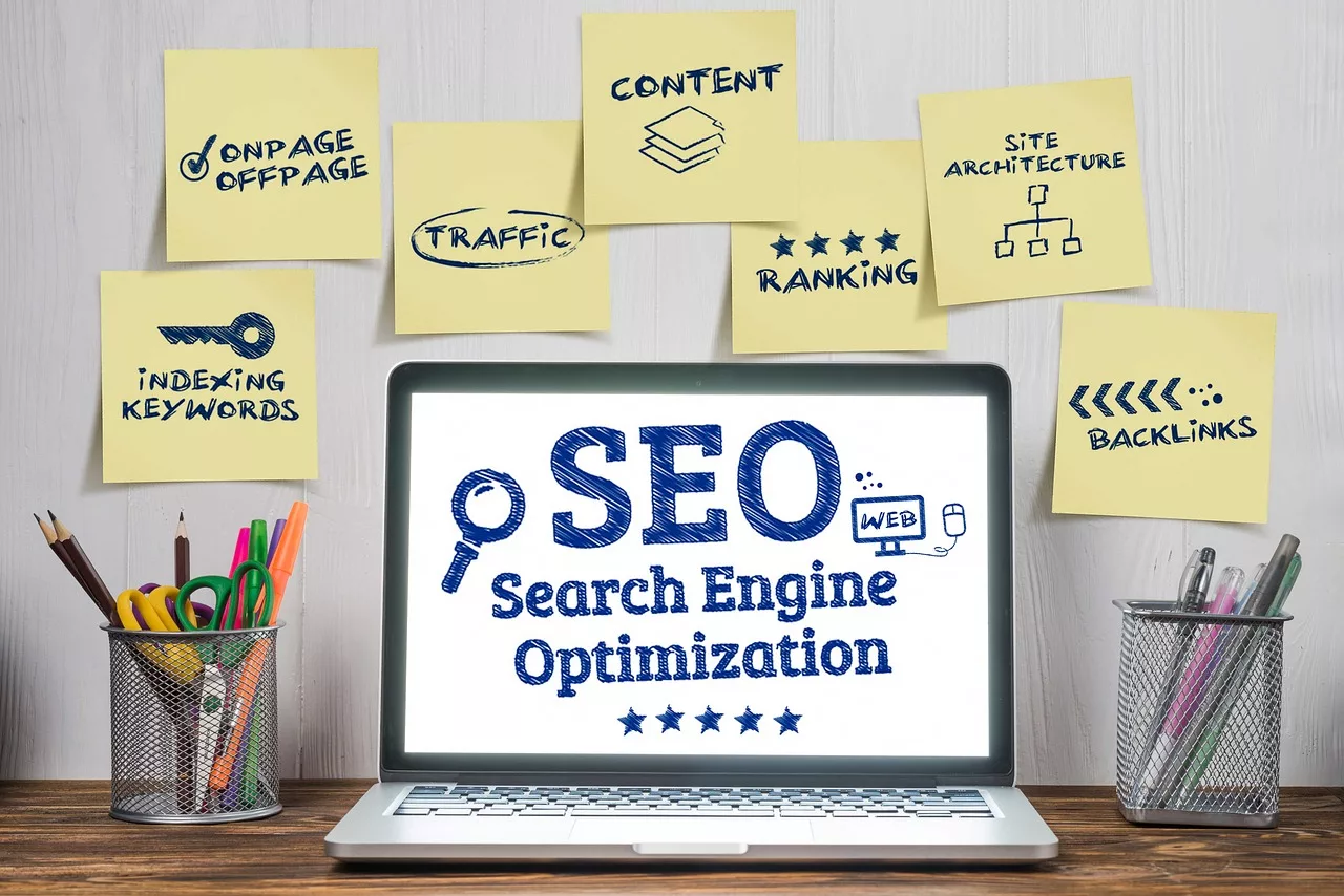 SEO strategies illustrated with sticky notes showing keywords like traffic, ranking, backlinks, and site architecture next to a laptop displaying 'SEO Search Engine Optimization'.